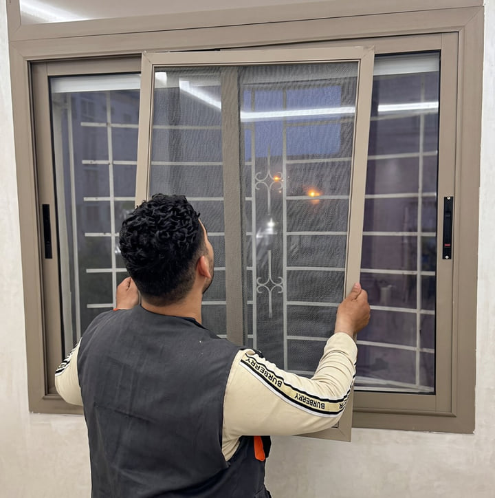 Technicien posant une moustiquaire aluminium sur mesure sur une fenêtre coulissante à Tanger — Aluminium Tanger