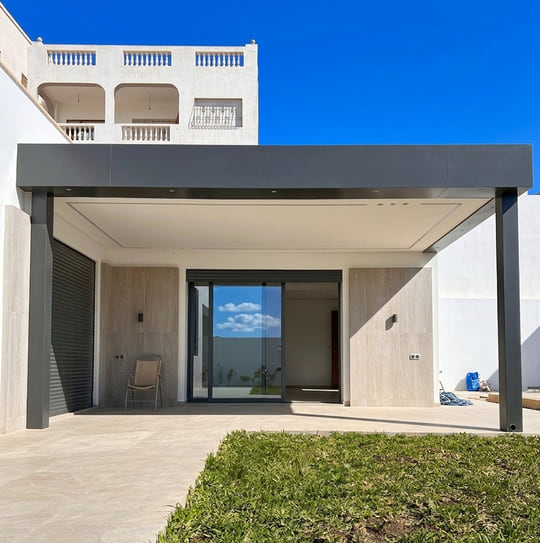 Pergola adossée à toiture plate en aluminium anthracite couvrant la terrasse d'une villa moderne avec baie coulissante à Tanger — Aluminium Tanger